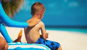 Mother applying sunblock cream on child shoulder